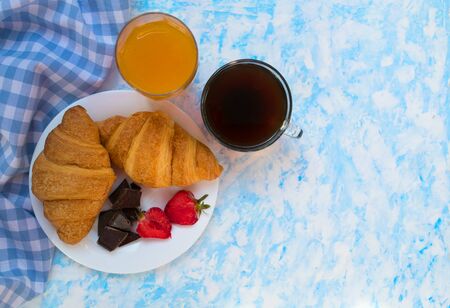 Two chocolate croissants strawberries, a cup of coffee and a glass of orange juice. Breakfast concept. Top view. Copy space.の写真素材