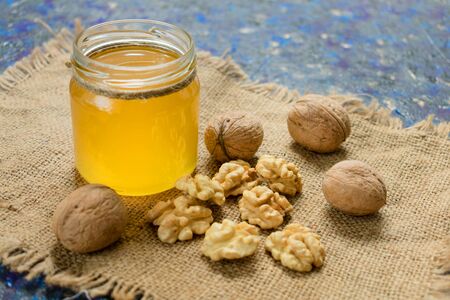 Jar of honey and walnuts on a blue background. The concept of healthy sweets.の写真素材