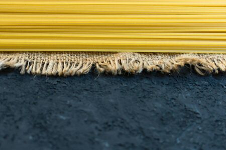 Raw long spaghetti on a black background. Yellow Italian pasta. Raw spaghetti bolognese. Copy space.の写真素材