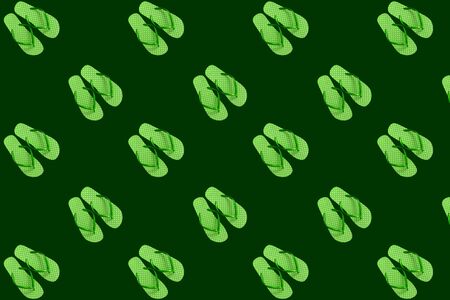 Seamless pattern from green flip flops on a dark green background.の写真素材