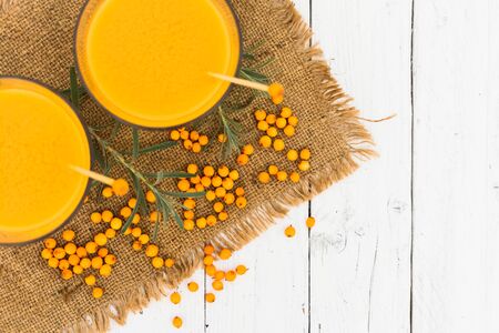 Two glasses of healthy vitamin sea buckthorn smoothie on a white wooden background. Top view.の写真素材