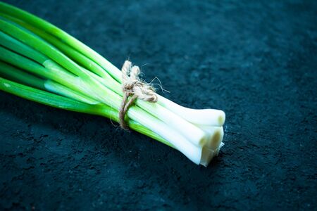 bunch of green onions on a black background texture. Close-up.の写真素材
