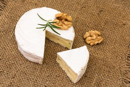 Camembert cheese with herbs, decorated with a sprig of rosemary and walnut. Close-up.の写真素材