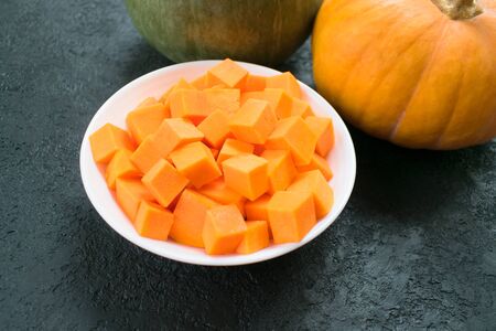 Slices of autumn pumpkins in a white plate on a wooden background. Top view.の写真素材