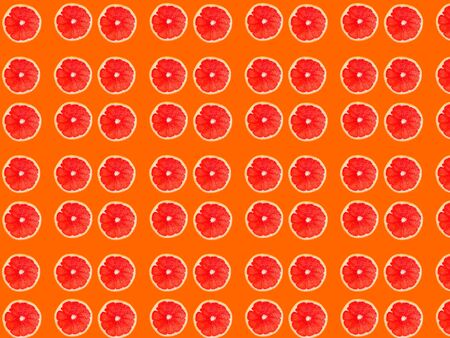 Seamless photo pattern of grapefruit slices on an orange background. Seamless pattern for your design.の写真素材