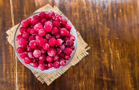 Frozen cranberries in a plate on a dark wooden background. Flat lay. Copy space.の写真素材