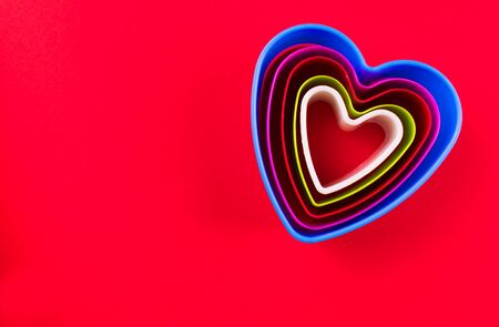 Cookie cutters in the form of hearts of different sizes on a red background. Copy space.の写真素材