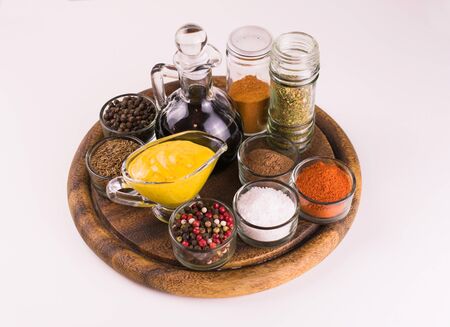 Sauces and various spices on a wooden board on a white table.