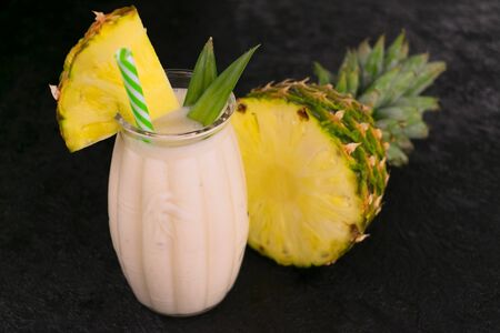 A large glass with pineapple smoothie on a black background.の写真素材