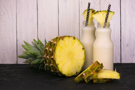 Two bottles with pineapple healthy smoothie and pineapple.の写真素材