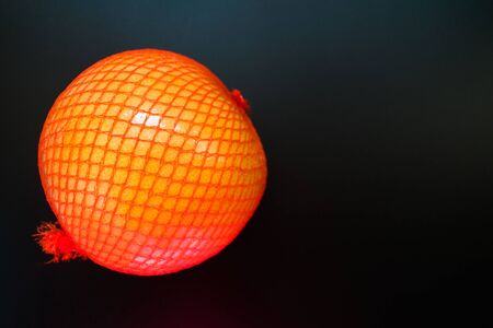 Pomelo in a packing net on a black background. Copy space.の写真素材