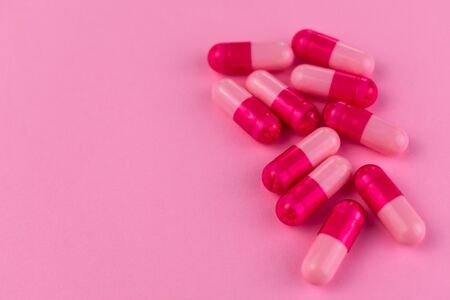 A lot of pink capsules, pills on a pink background. Copy space.