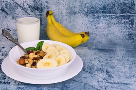 Plate with granola with banana and milk on the table. Copy space. Delicious and healthy breakfast.の写真素材