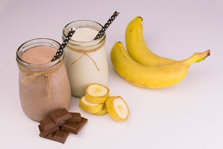 Two servings of chocolate and banana milk smoothie on a white background.の写真素材