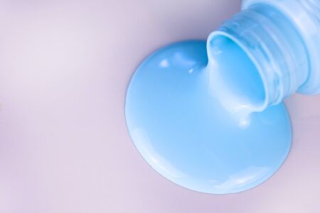 Light blue paint pouring from a bottle on a white background. Copy spaceの写真素材