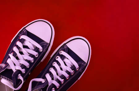 Blue sneakers or sneakers on a red background.Copy space.