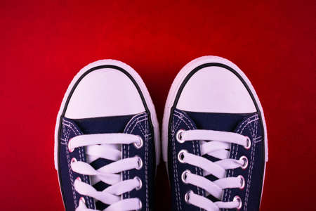 Blue sneakers or sneakers on a red background.Copy space.