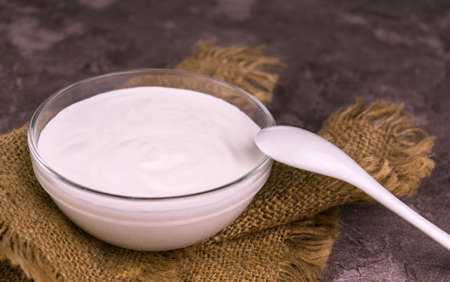 Sour cream in a transparent bowl on the table. Close-up.