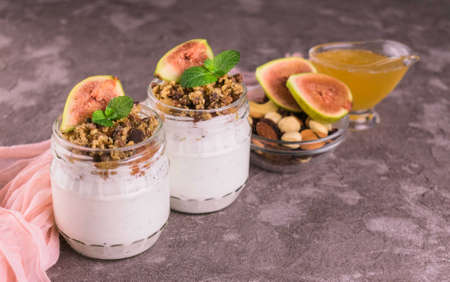 Two jars with fig yogurt, berries and honey on a gray background.の写真素材