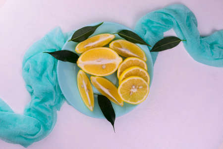 Sliced â€‹â€‹lemons on a blue plate on a white background. Flat lei.