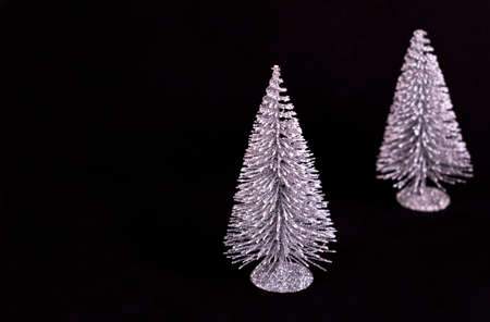 Two shiny Christmas trees on a black background. Copy space.の写真素材