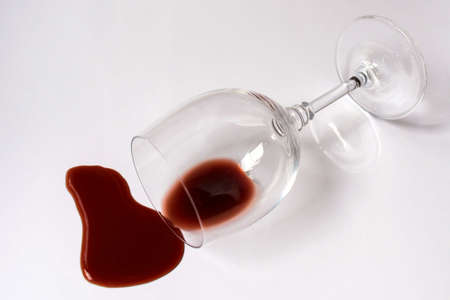 Glass with spilled red wine on a white background. Copy space.