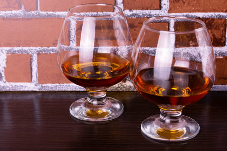 Two glasses with cognac on a brick wall background.