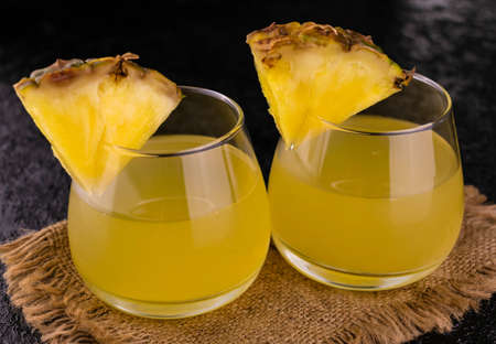 Two glasses with pineapple juice on a black background. Close-up.の写真素材