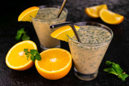 Mint orange smoothie in high glasses on a black background.の写真素材