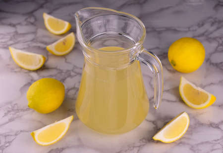 A jug of lemon juice on a white marble background. Top view.の写真素材