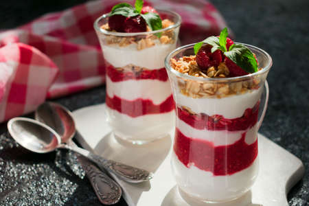 Two glasses with fresh raspberries and cream cheese on a black background. Healthy homemade organic...