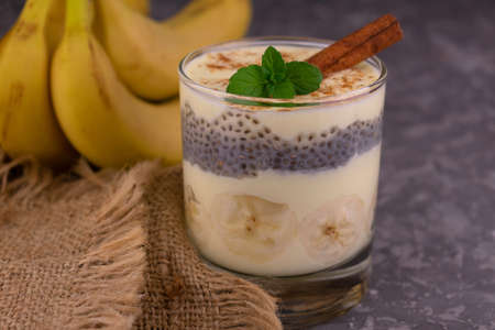 Banana yogurt with cinnamon in a glass on a gray background. Close-up.の写真素材