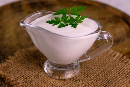 Sour cream in a glass gravy boat with parsley. Close-up.の写真素材