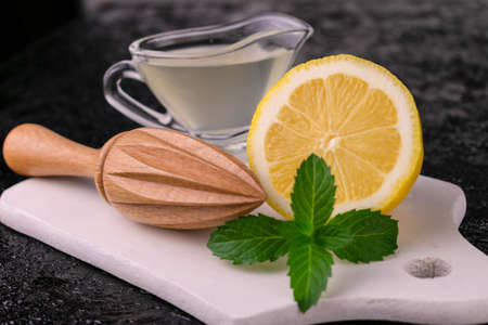 Freshly squeezed lemon juice in a glass gravy boat on a black background.
