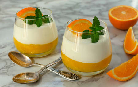 Dessert with mascartone and orange curd in glasses on a white marble background.