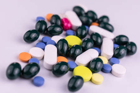 Many multi-colored pills on a white background. Close-up.