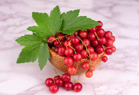 Red currant berries in a bowl on a white background. Close-up.