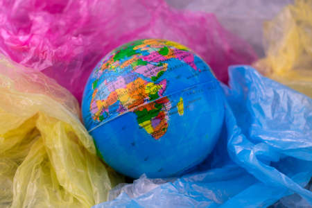 Planet model sinking in a pile of plastic bags. Concept of Saving Our Planet Earthの写真素材