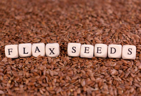 The inscription flax seeds on the background of flax seeds. The concept of natural vitamins and microelements.の写真素材