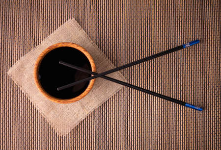 Soy sauce and chopsticks on a bamboo mat, top view.の写真素材