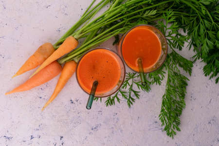 Carrot juice and fresh carrots on a white plate. Flat lay.