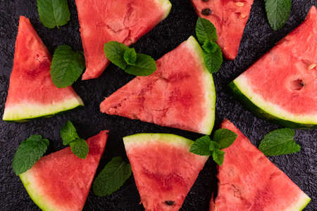 Sliced ââwatermelon and mint leaves on a black background. Flat lei.の写真素材