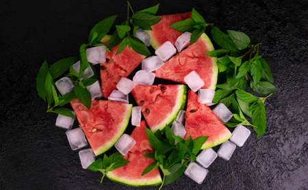 Slices of watermelon, mint and ice cubes on a black background. Flat lay.の写真素材