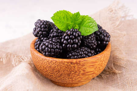 Blackberries in a wooden bowl on a white background. Close-up.