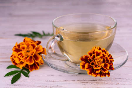 Medicinal marigold tea in a transparent cup on a white wooden background.の写真素材