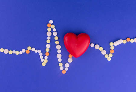 Heart of cardiograms from color pills on a blue background. Concept of heart disease.の写真素材