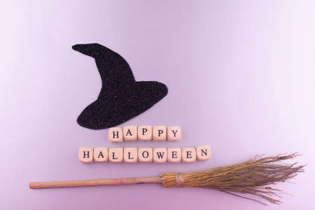 Black witch hat, broom and happy halloween lettering on gray background.の写真素材