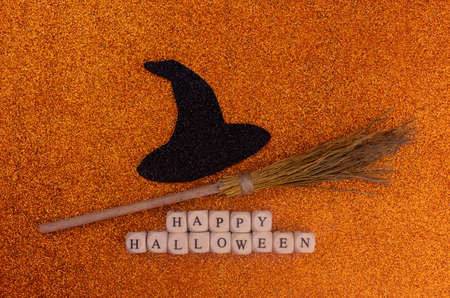 Black witch hat, broom and happy halloween lettering on shiny orange background.の写真素材
