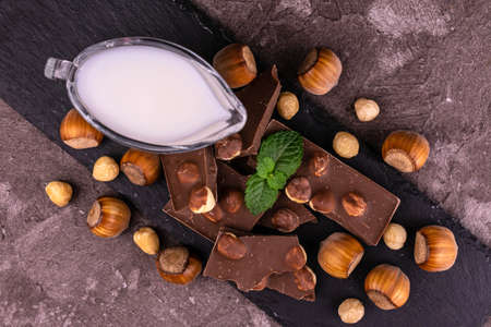 Milk chocolate with hazelnuts and milk on a wooden background. Flat lei.
