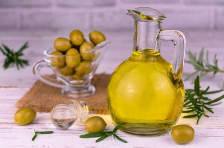 Olive oil in glass gravel fresh olives and rosemary on a white background.の写真素材
